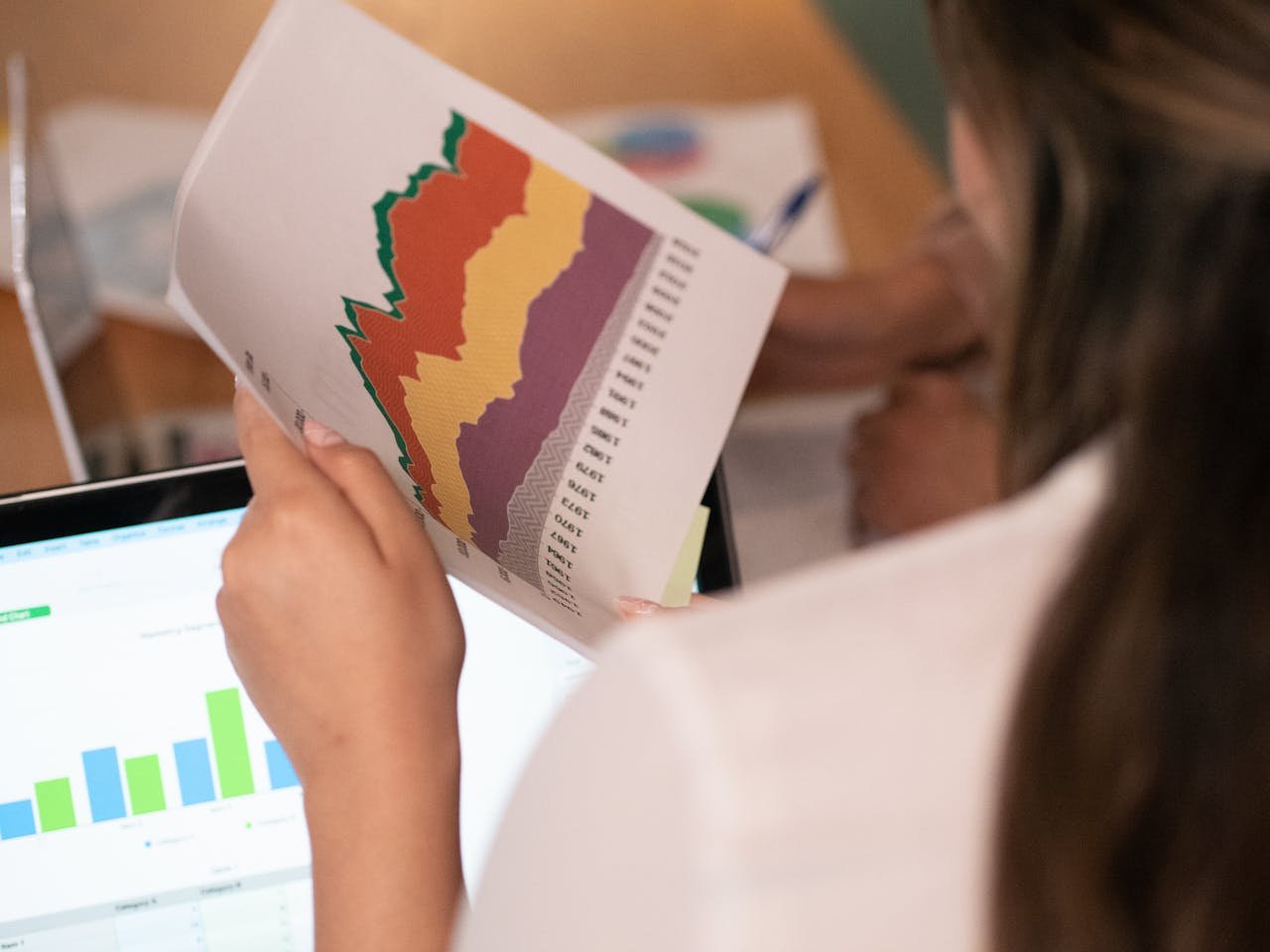 our-story-02 Close-up of a woman analyzing colorful charts and graphs in an office setting.